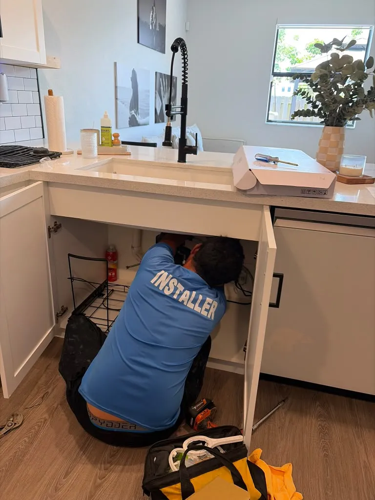 Installer working under a kitchen sink